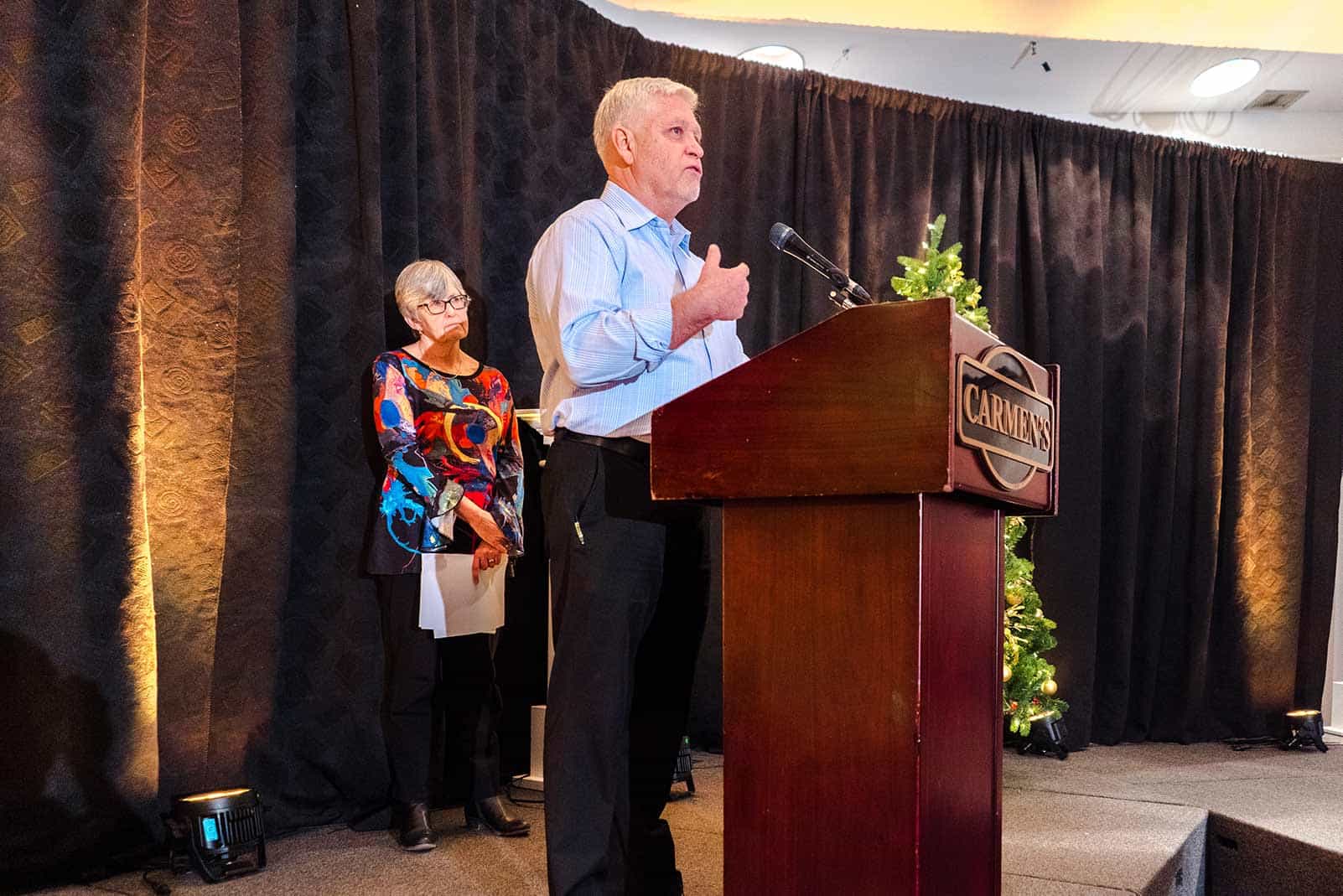 René and Eileen stand on stage behind the podium